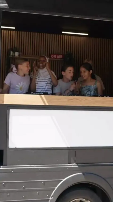 A group of children in a van performing DJ skills.