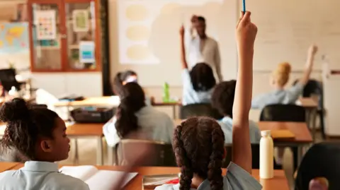 A scene of children raising their hands in a classroom