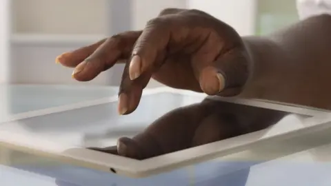 Getty Images Hand over tablet computer