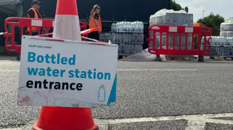 Bottles of water at an emergency outdoor centre in Herne Bay with a sign and cones.