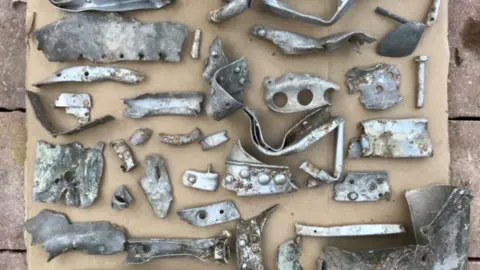 Danny Jones Dozens of metallic Spitfire components laid out on a sheet of cardboard. They are all varying shapes and sizes.