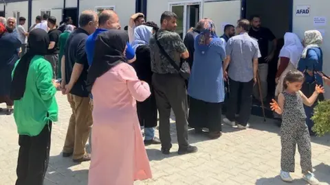 Michael Ertl/BBC Voters in Antakya queued outside portable containers because the polling stations were unsafe