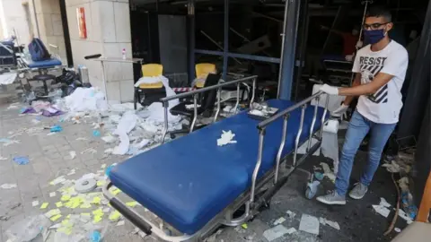 Reuters A man wearing a face mask moves a gurney at a damaged hospital following Tuesday"s blast in Beirut, Lebanon August 5, 2020.