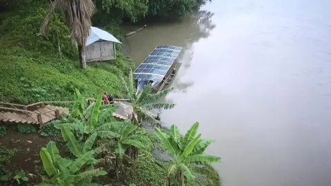 The solar canoe tied up at a village port