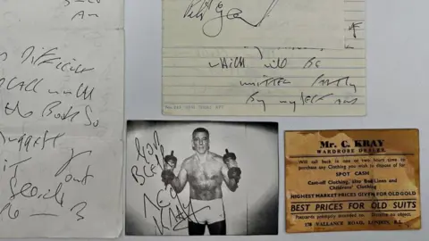 John Rolfe Auctions A signed black and white photo of Kray boxing and a brown business card from his father