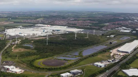 Nmuk Aerial view of solar and wind farms next to Nissan