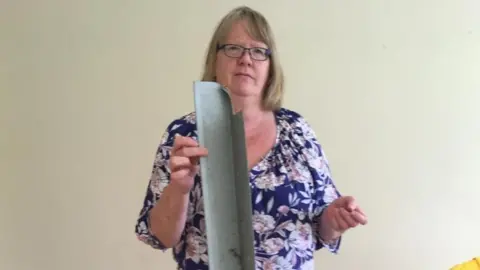 Pauline Sadler holds a piece of cladding