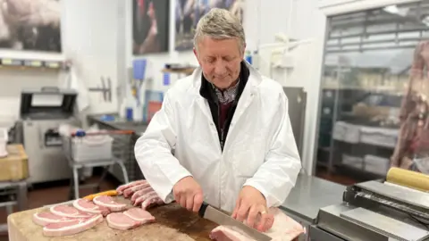 Martin GIles/BBC Butcher Jeremy Thickitt cutting up pork chops