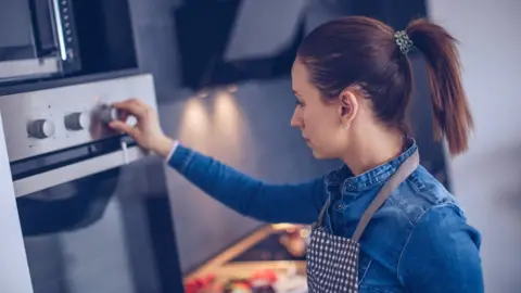 Getty Images Woman using gas cooker