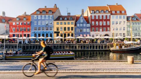 A cyclist passes a row of colourful houses