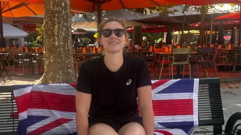 Sam Farrow/PA Sam Farrow sitting on a bench with a Union flag behind her 