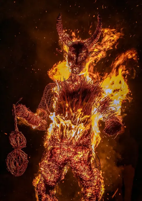 Craig Bradshaw A straw devil sculpture on fire, with the flames blazing away