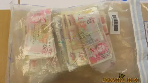 Jersey Customs and Immigration Services A ziplock transparent plastic bag in which bundles of £20 notes are held with elastic bands. There is a date stamp on the photo which reads 23.06.2023 08:50 tdiqtiqduiuzprw