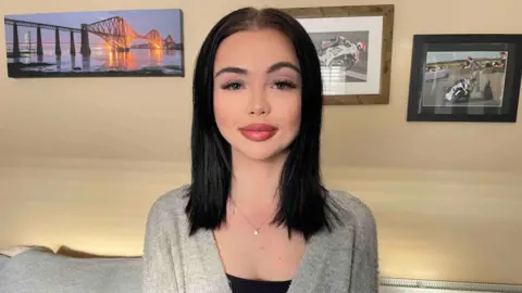 BBC A woman with dark hair. She is wearing a grey cardigan.