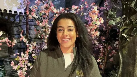 Mica Dougan, Head of Pilgrim Affairs stands in a pink flower decorated room at The Canterbury Tales