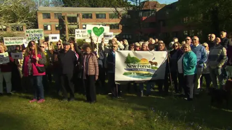 Crowds of people stood with signs outside the New Forest District Council offices.
