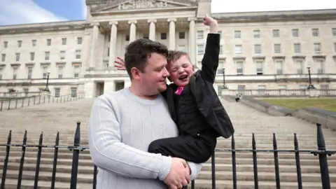 Liam McBurney/PA Máirtín Mac Gabhan and his son Dáithí were pictured at Stormont when the law came into force last summer