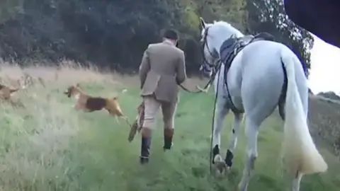 Warwickshire Police A man in a tweed suit walking next to a white horse and two hounds