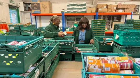 Two women sorting done  greenish  crates containing nutrient  successful  a nutrient  bank