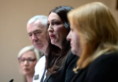 PA Michelle O'Neill, Jon Boutcher, Emma Little Pengelly and Naomi Long. They stand behind podiums.