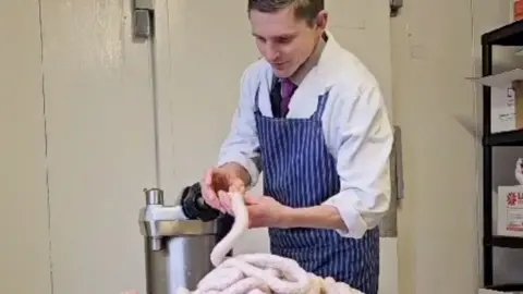 Butcher filling sausages.