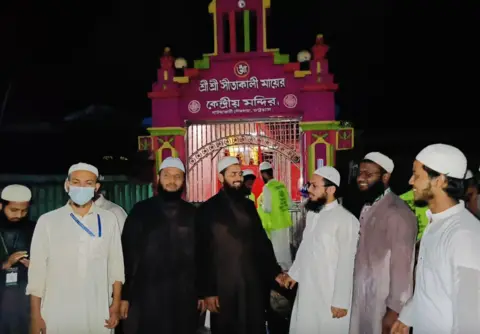 A group of Muslim men stand in front of a local Hindu temple. 