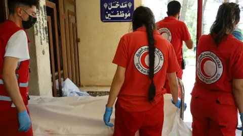 Syrian Red Crescent rescuers stand next to the body of a victim of the recent clashes in Suweida province, at a hospital in Suweida city (17 July 2025)