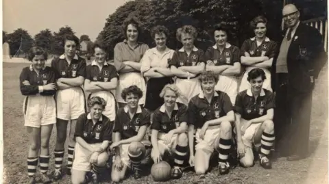 Films Not Words A group of players, wearing a football kit, are posing for a team photograph on a field in 1958.