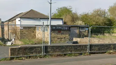 A closed two-story brick building surrounded by silver metal fences