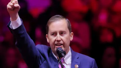 Reuters Sergio Gor at a Trump Rally speaking at the lectern with his fist raised in the air.