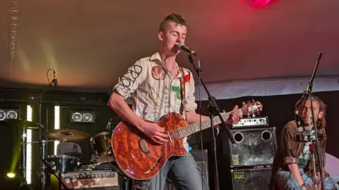 Supplied A man playing an electric guitar on stage