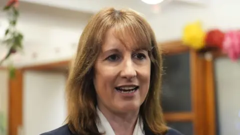 Rachel Reeves wearing a white blouse, dark blue jacket, with shoulder length hair