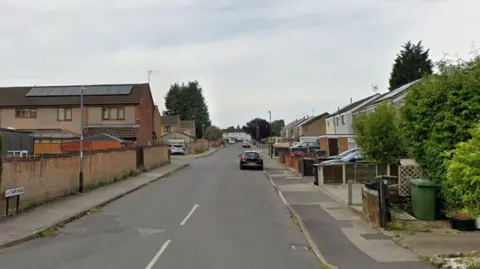 Google Whitburn Road in Bedworth, with houses and pavements on either side of the street and parked cars.