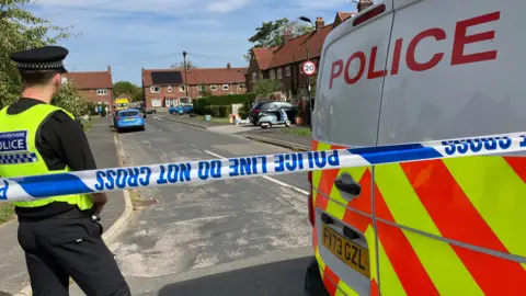 A policeman and police van are pictured inside a police cordon on a residential street in York.