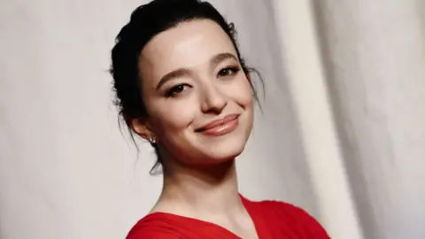 Getty Images Mikey Madison attends the Virtuosos Award ceremony during the 40th annual Santa Barbara International Film Festival at The Arlington Theatre on February 09, 2025 in Santa Barbara, California. She has her dark hair swept up and is wearing red.