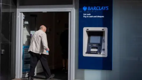 Getty Images Man walking into a Barclays bank branch