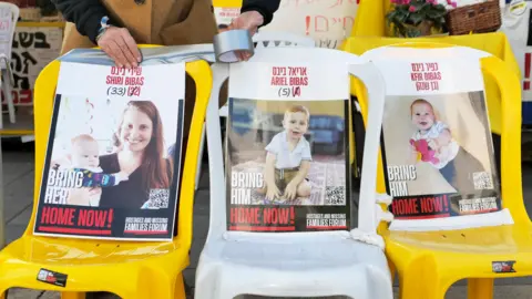 A woman from EPA touches a picture of the Israeli hostage, along with pictures of her two children, in a protest camp for hostages families in Jerusalem on February 19, 2025. 