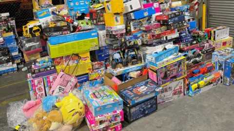 South Australia Police Large pile of toys including Pokemon soft toys, water guns, toy trucks on a warehouse floor