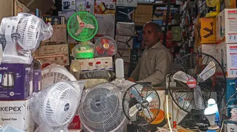 Getty Images A vendor selling table fans waits for customers at a summer market in Varanasi on May 27, 2024