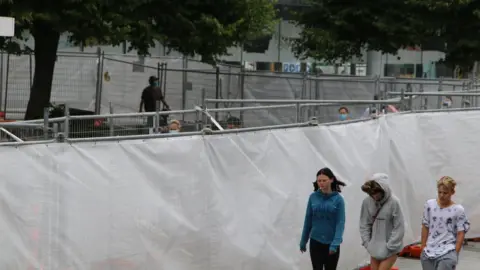 Getty Images Members of the public walk within meters of those staying in enforced isolation in Christchurch, New Zealand