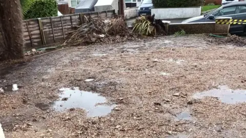Dorset Council A patch of uneven soil and large puddles of water in a property's garden. 