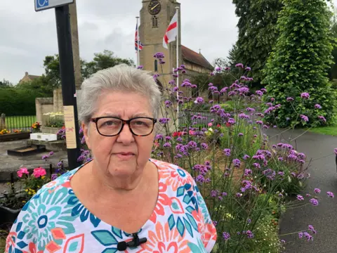 John Devine/BBC Anne Wells, chair of Chatteris in Bloom outside the parish church in town