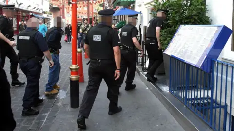 PA Media A group of uniformed police officers enter a restaurant in London's Chinatown.
