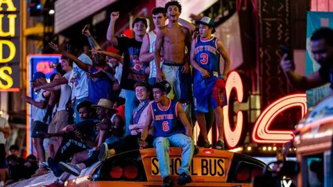 Fans in New York celebrate on top of a school bus