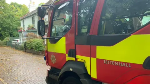 A fire engine with the name Tettenhall dominates the right side of the picture, with at least two older properties stretching off to the left of the image