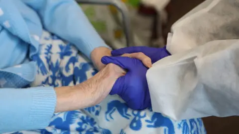 PA Media Care workers gloved hands old elderly woman's hands