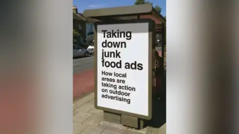 An advert on a bus stop reads 'taking down junk food ads'