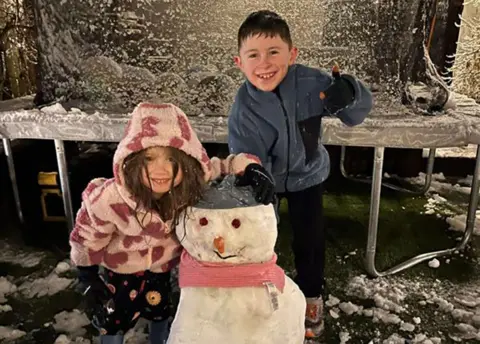 Ian Court Two children posing with a snowman