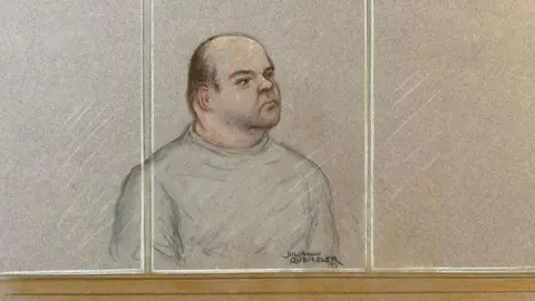 Julia Quenzler/BBC A court sketch of Gavin Plumb, who is wearing a grey sweatshirt and sat in the dock