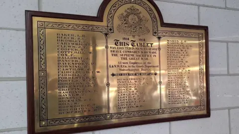 West Midlands Trains The memorial plaque, which is on a wall, contains the names of more than 60 people. They are listed in three columns.